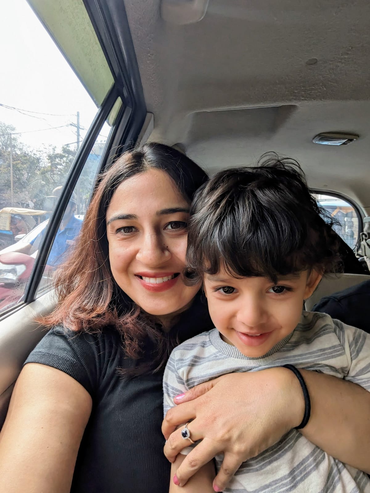 Nikhila and her son smiling together in a car