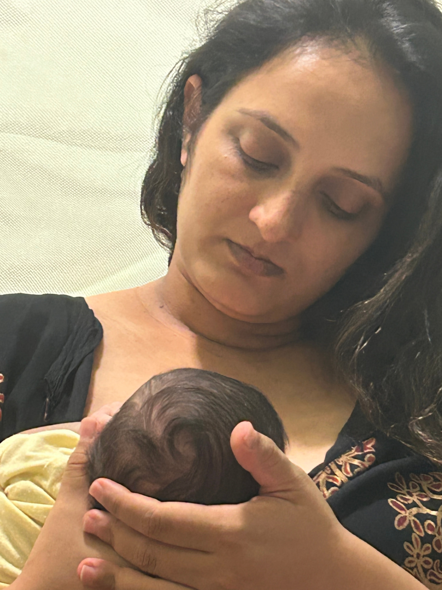 Ramya cradling her newborn close to her chest