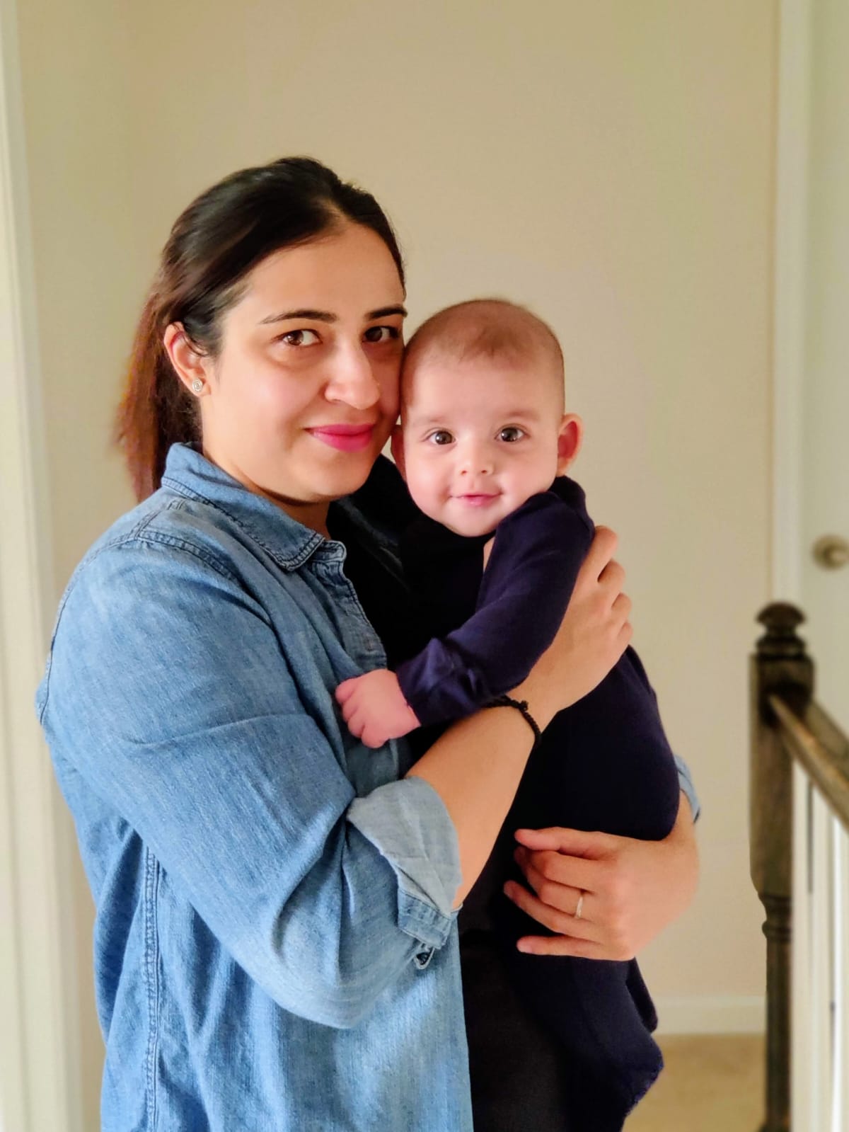 Nikhila holding her baby close at home
